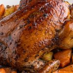 Whole juicy herbed roast chicken with golden skin, garnished with parsley and lemon, served on a platter for a family-style feast