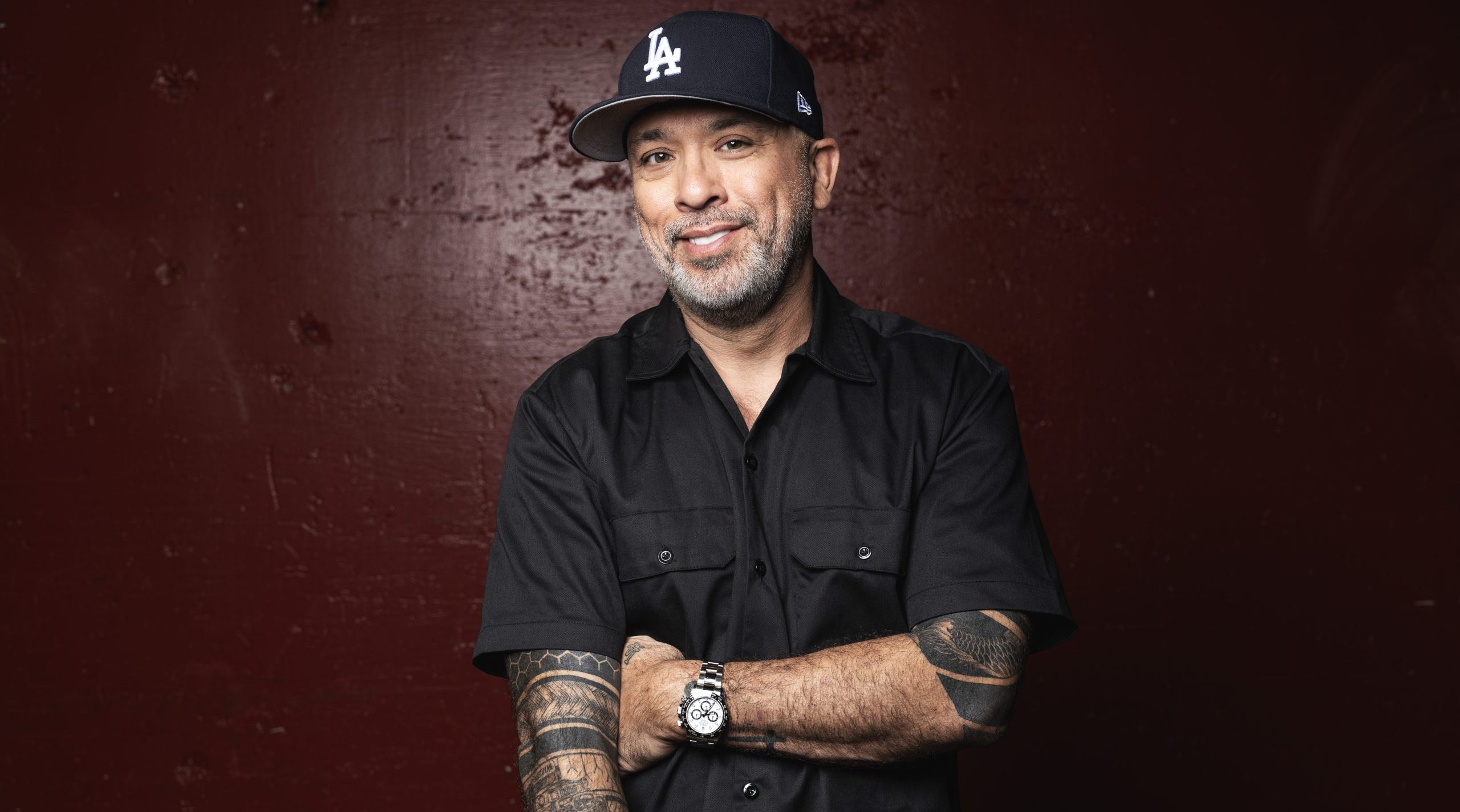 Portrait of Jo Koy smiling in a casual black jacket, standing against a clean background; Filipino-American comedian known for family-based stand-up comedy and global tours.