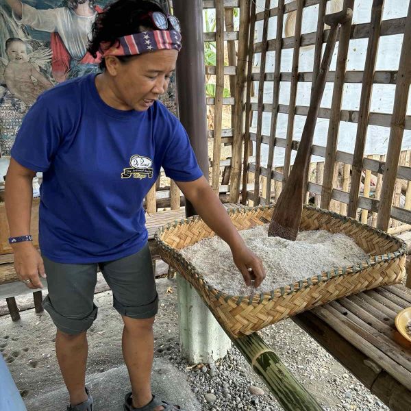 A resource person inspects freshly roasted granules of Miag-ao artisanal sea salt—each batch a result of hours of careful filtering, drying, and hand-roasting.