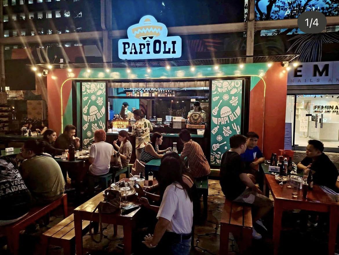 Night crowd at Papi Oli Katipunan enjoying tacos and street food under warm lights—a lively barkada vibe in Quezon City.