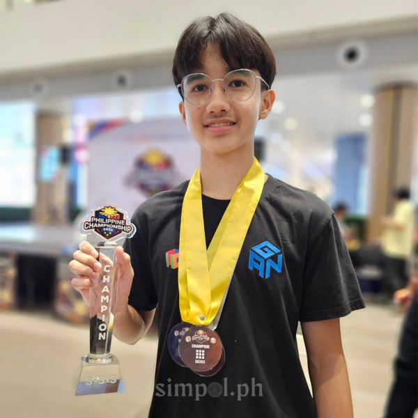 Leo Borromeo proudly holding his trophy and medal after winning a national Rubik’s Cube championship—symbol of quiet mastery from a Cebuano teen.”