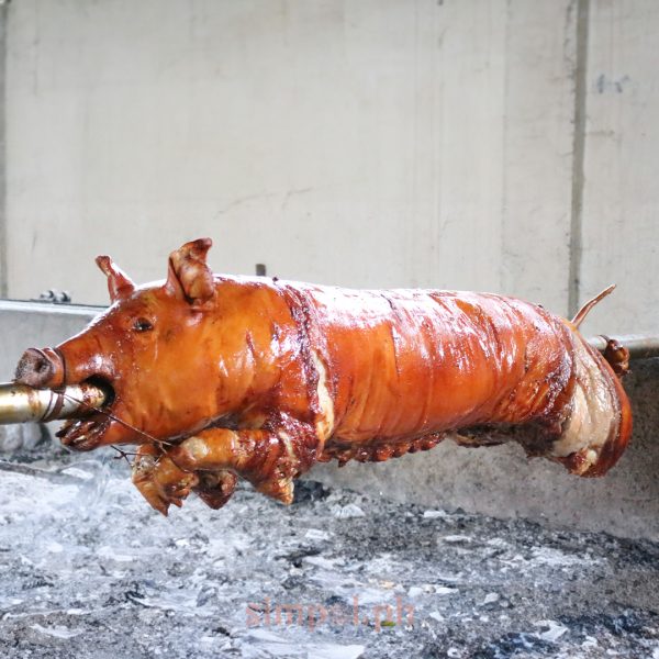 Whole lechon roasting over open coals at House of Lechon Cebu, basted continuously for crisp skin and bold flavor.
