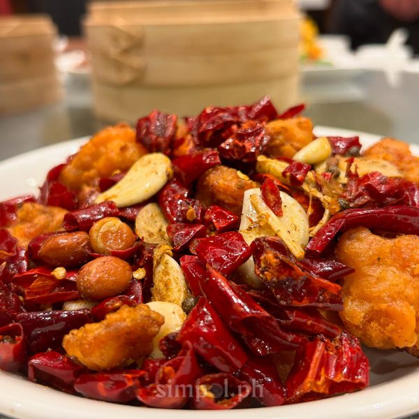 Spicy Szechuan chicken dish from Paradise Dynasty, topped with dried chilies, garlic slivers, and toasted peanuts, served sizzling hot.