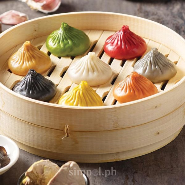 Eight colorful xiao long bao arranged in a bamboo steamer, showcasing the variety of flavors at Paradise Dynasty, a top spot for Szechuan cuisine in Manila.