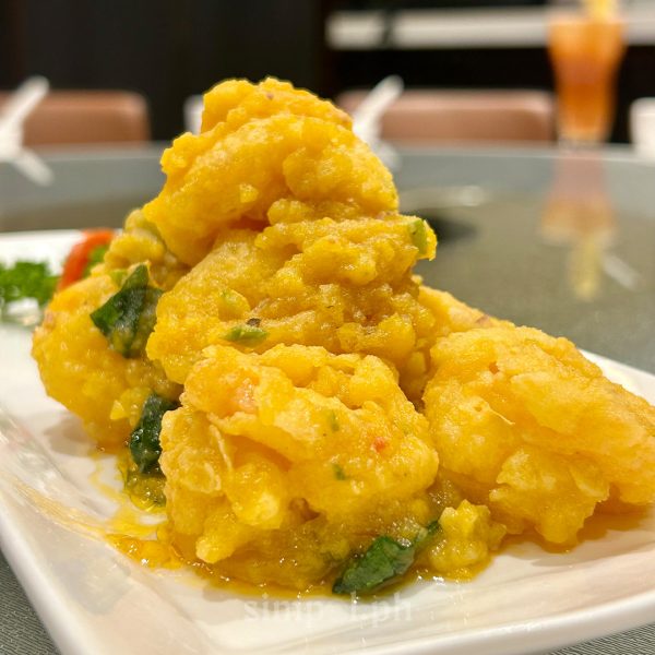 Close-up of salted egg crystal prawns glistening in golden yolk, served at Paradise Dynasty, known for refined Szechuan cuisine in Manila.