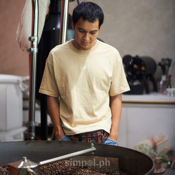 Philippine coffee content creator Timdrinkscoffee observing roasted beans in a local roastery, showcasing his thoughtful approach to the coffee transformation process.