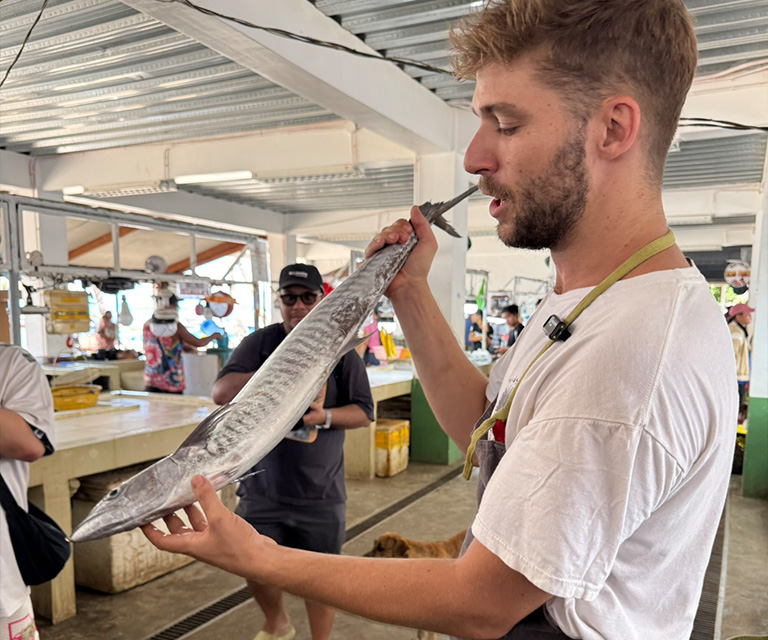 Chef Filippo Turrini holding Spanish mackerel before preparing ceviche at the General Luna market.